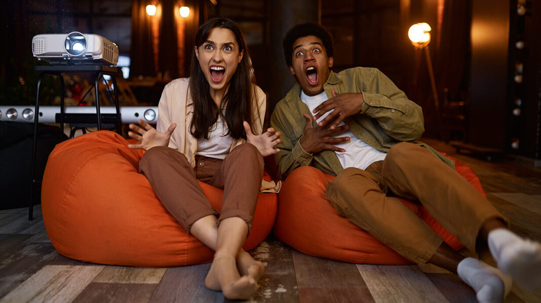 Scared couple watching horror movie at home